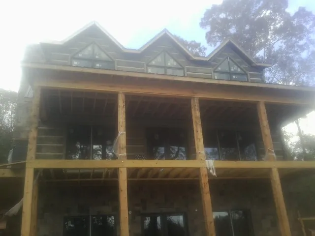 Dormers and porch framing on a large log home under construction — Roof Coating work by our crew in Alcalde