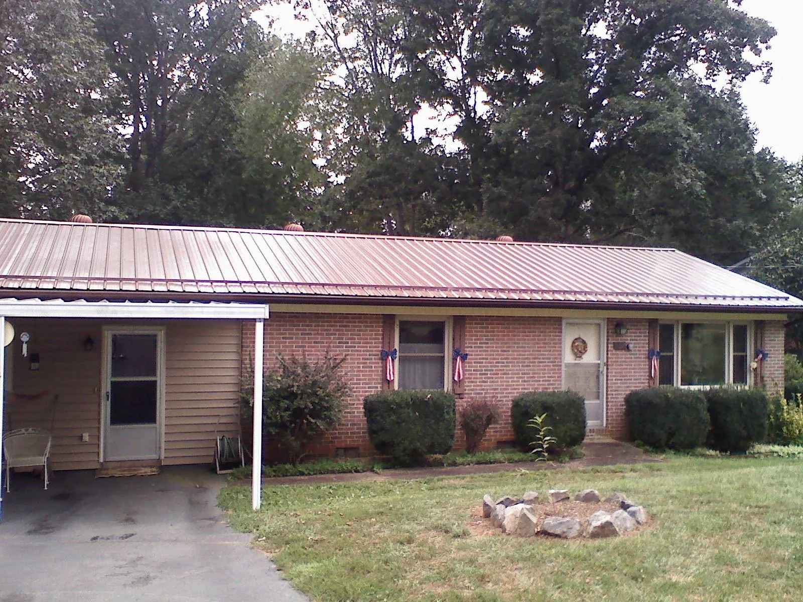 Bronze metal roof and carport on a brick ranch home — Roof Repair work by our crew in Alcalde